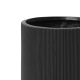 Close-up of the upper half of a black, ribbed cylindrical vase, crafted from magnesium oxide material, featuring a smooth interior.