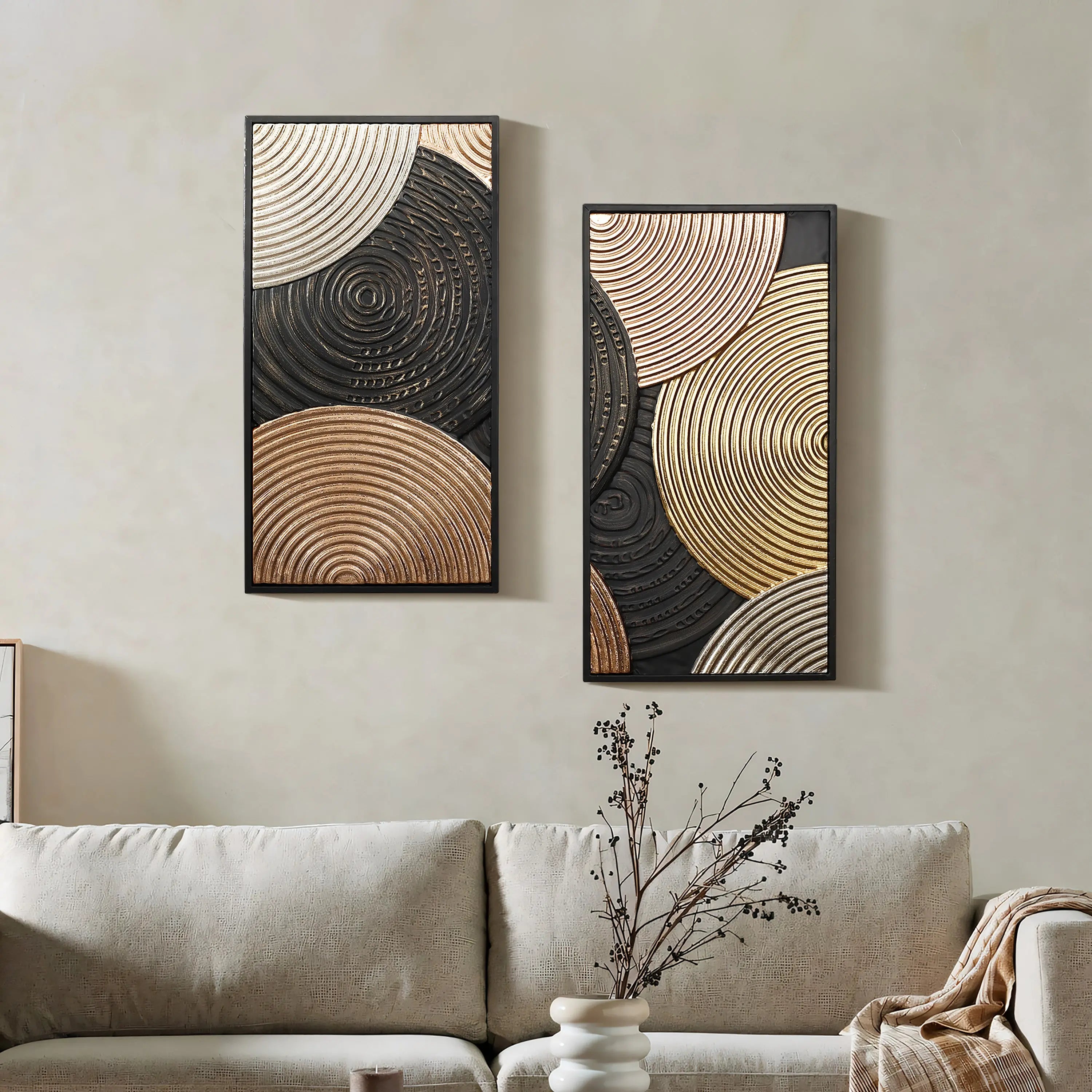Two abstract wall decor art pieces featuring circular patterns in gold and black, with intricate embossed textures, are elegantly hung above a beige sofa. A small vase sits on a side table, adding a touch of charm to the scene.
