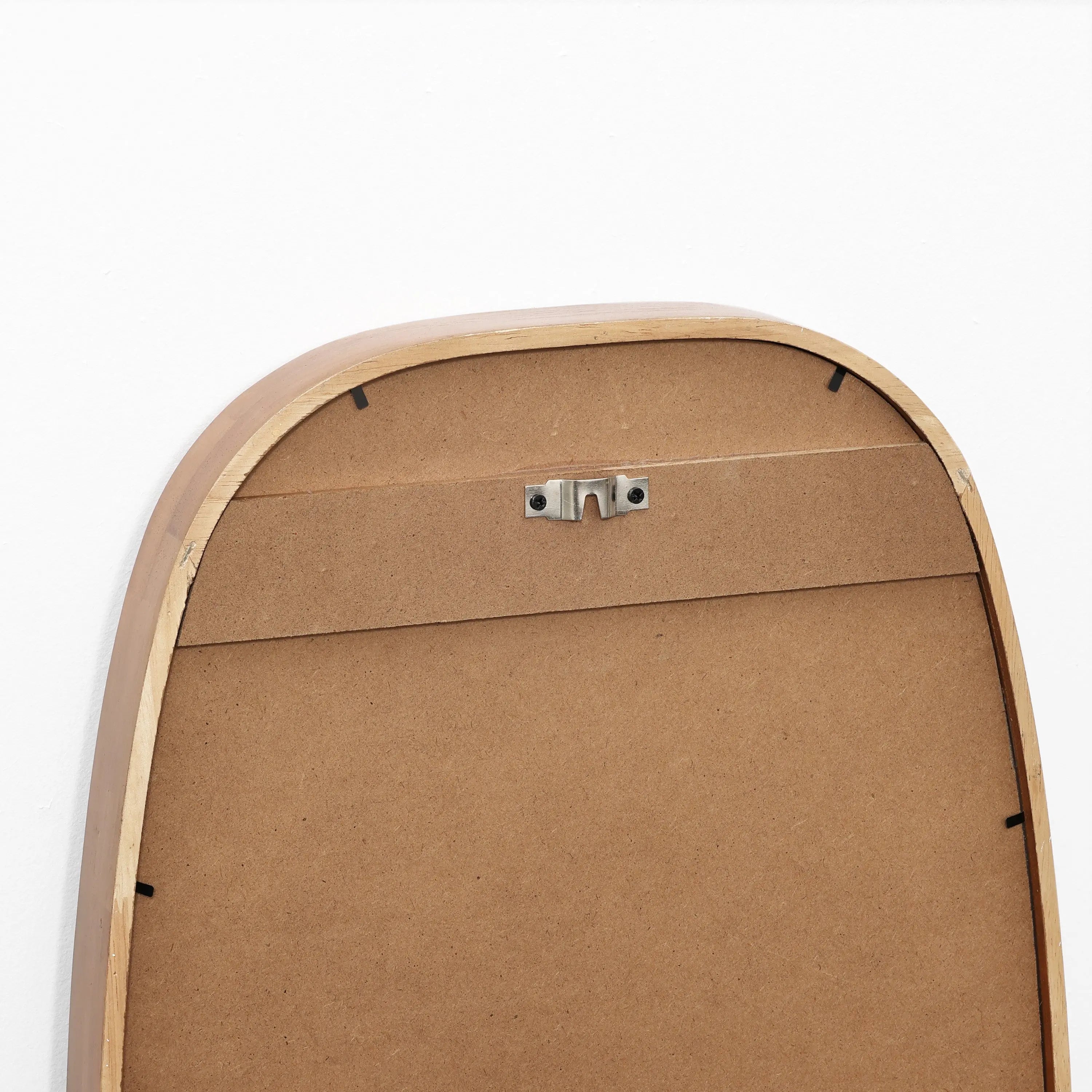 The back of this handcrafted rubberwood mirror with a metal hanging bracket is shown against a white wall, showcasing its contemporary style.