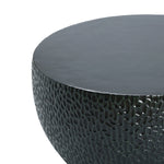 Close-up of a round, textured surface resembling a black cement outdoor coffee table.