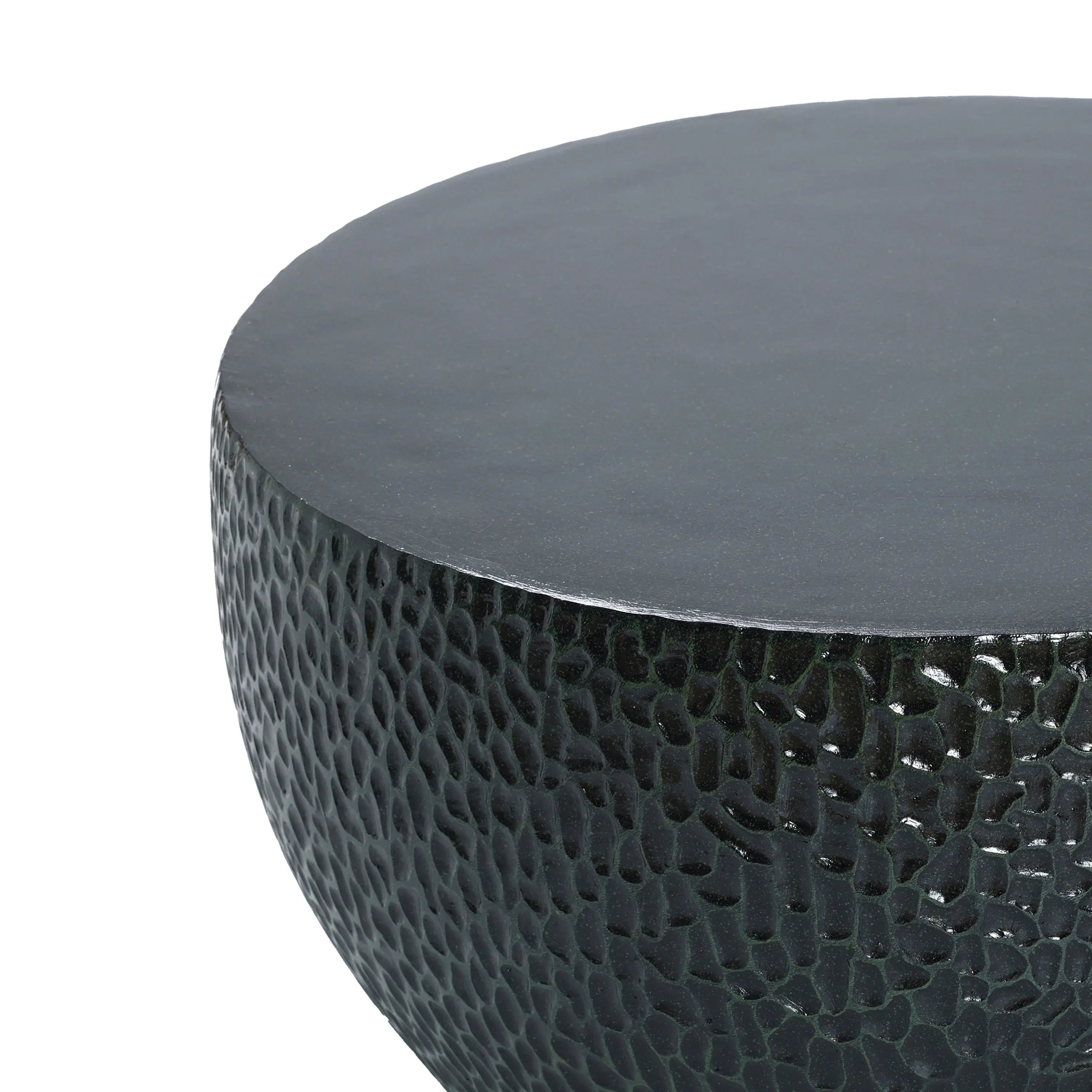 Close-up of a round, textured surface resembling a black cement outdoor coffee table.