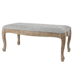 Upholstered bench with a light grey linen upholstery and wooden legs, blending old-world charm with modern simplicity, photographed against a white background.