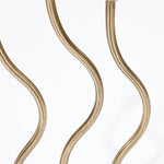 Close-up of three vertical, wavy gold metal rods, resembling an elegant candle holder, against a clean, white background—a perfect touch of sophistication for home decor.