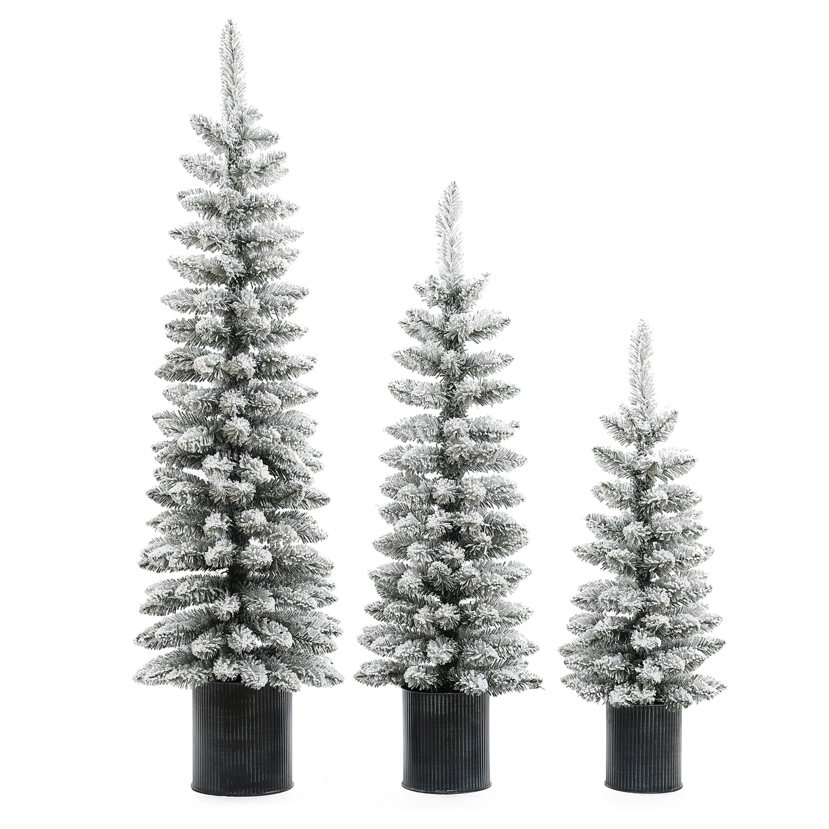 Three flocked artificial trees with PVC branches of varying heights stand side by side in black ribbed pots, bringing a wintry charm to your space. These lifelike Christmas trees are beautifully snow-frosted against a crisp white background.