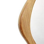 A close-up of a wooden frame with a smooth, curved edge and visible grain embodies a natural elegance. Its organic design seamlessly adapts as a versatile accent in any room, enhancing the charm with its rich texture and warmth.