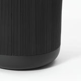 Close-up of a black cylindrical object with vertical ridges and a smooth base, resembling the sleek design of a stripes pattern planter, on a white background.