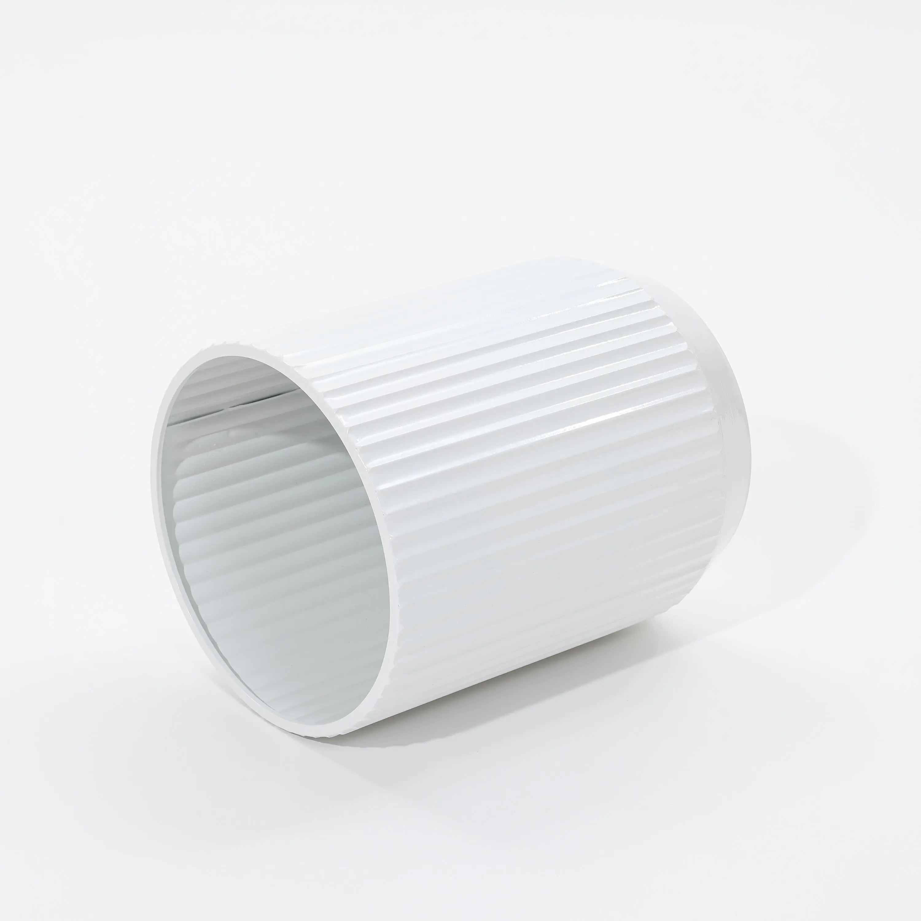 A sleek, white, cylindrical object with vertical ridges lies on its side against a white background, reminiscent of modern metal plant pots in its streamlined design.